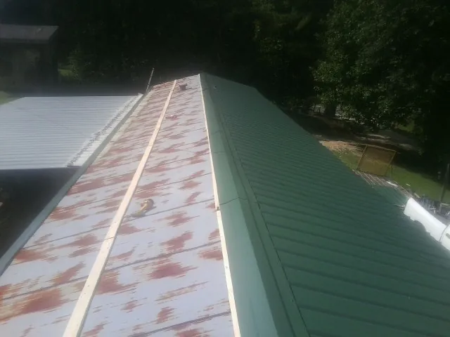 Old rusted panels beside newly installed green metal roofing — Wind Damage Roof Repair by Roofing Brothers in North Fairfield