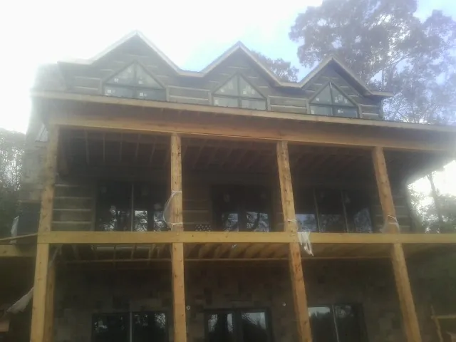 Dormers and porch framing on a large log home under construction — Roof Coating work by our crew in North Fairfield