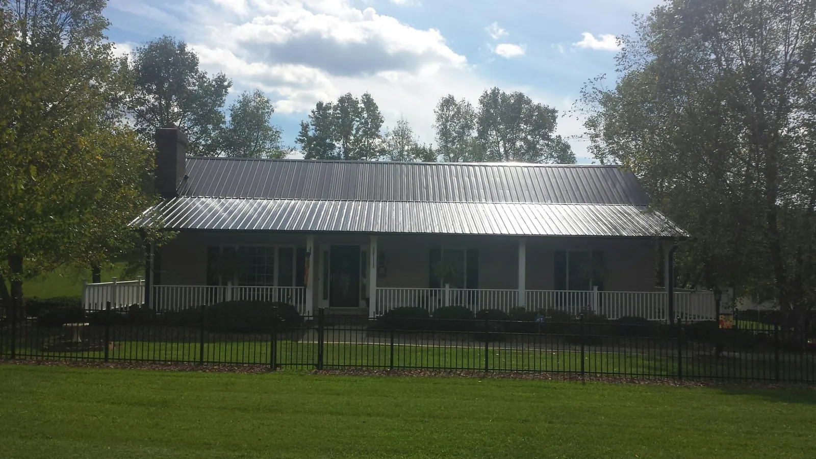 Gray metal roof on a brick ranch with a full width front porch — Gutter Guard Installation work by our crew in North Fairfield