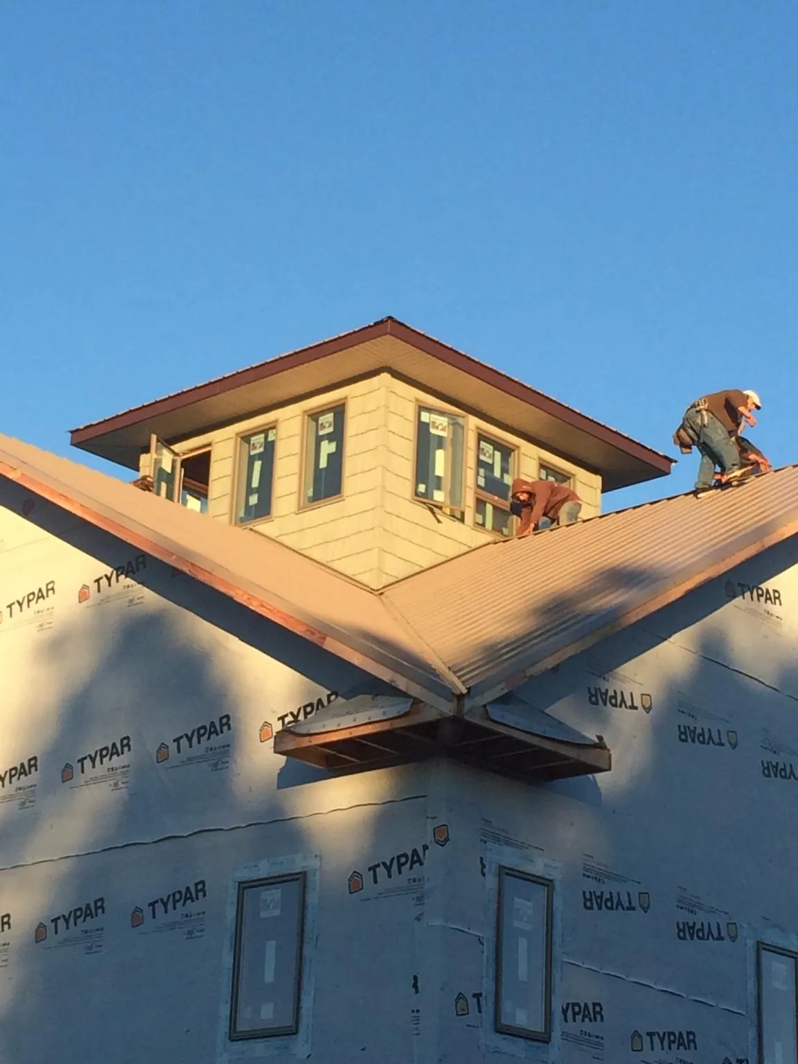 Roofers working around a rooftop cupola on a new metal roof at sunset — Roof Waterproofing in North Fairfield by Roofing Brothers